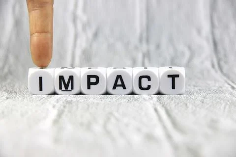 Impact wording  or text on white dice with hand.White wooden background.Cop.. Stock Photos