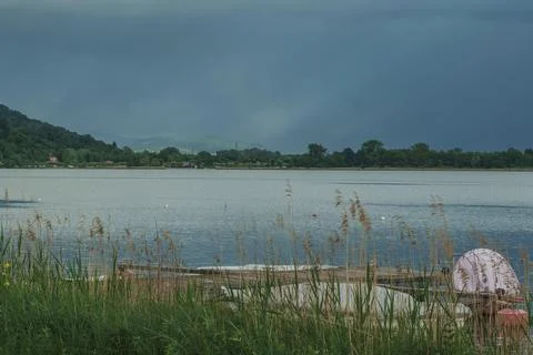 Impending storm clouds gathering over a peaceful lake landscape Stock Photos
