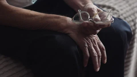 Impersonal old man sitting on the sofa holds glasses in his hands. lifestyl.. Stock Footage 250223022