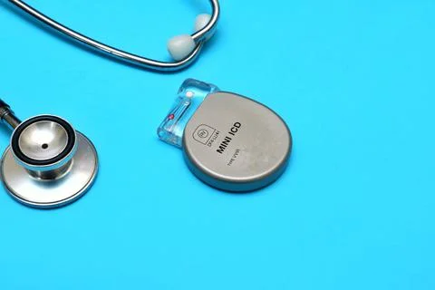 An implantable pacemaker device and a stethoscope on a blue background. Foto stock