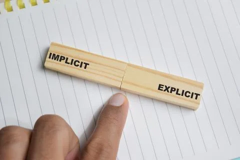 Implicit or explicit on stacked wooden cubes on the table. Stock Photos
