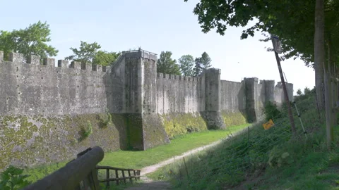 Imposing ancient stone fortress wall featuring fortification towers and a grassy Stock Footage 336133879