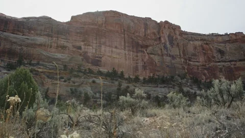 Imposing vast red rock cliffside face of mountain with sun flare, slow motion Stock Footage 248581300