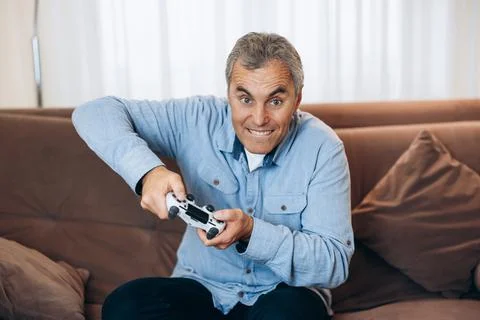Impossible to put down Mature man is completely absorbed in playing his favorite Stock Photos