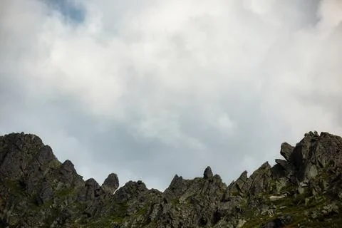 Impregnable jagged rocks against a cloudy sky Stock Photos