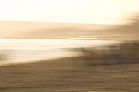 Impressionistic deliberate blur of sandy beach and sea at sunset Stock Photos