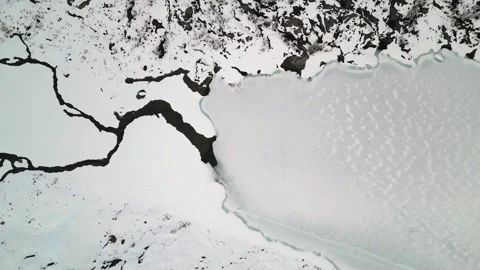 An impressive aerial perspective captures a snowy valley, where a frozen river Stock Footage 295923919