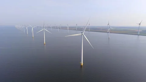 An impressive array of windmill turbines rotates gracefully over the calm sea in Stock Footage 331281138