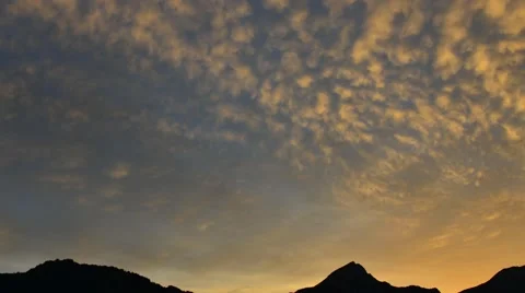 Impressive clouds painted in sunset colors move across the sky. Time Lapse Stock Footage 53875136