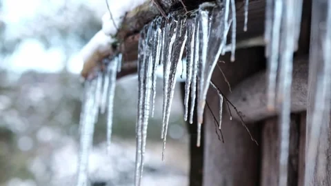 Impressive crystal clear icicles forming on the roof of a wooden cabin in the Stock-Footage 330878580