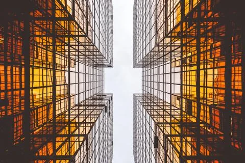 An impressive low-angle shot of two modern glass facades reflecting orange .. Stock Photos