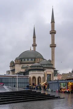 Impressive mosque architecture under a cloudy sky with people walking. Istanb Stock Photos