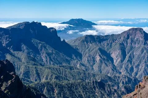 Impressive mountain range of volcanic rock with a volcano emerging from the Stock Photos