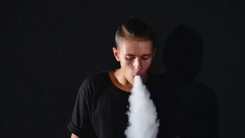 Impressive smoke circles are made by a young man, who uses an electronic Stock Footage 79532781