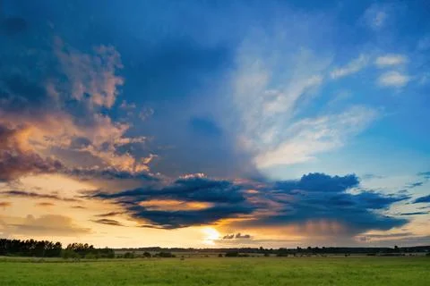 Impressive storm clouds illuminated by the sunset over the rural landscape Stock Photos