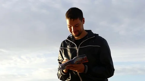 Impressive Sunset and a Silhouette of a Man Writing Down Something Into His Stock Footage