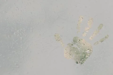 The imprint of a human palm on a translucent, misted glass. Spring rain drops Stock Photos