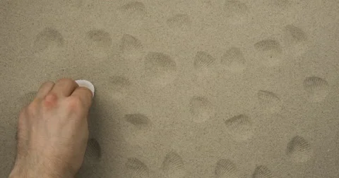 Imprints of a seashell on the sand. In real time. A male hand makes shell Stock Footage 136458656