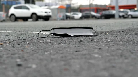 Improperly disposed face mask lying on asphalt in store car park Vídeos de archivo 182891778