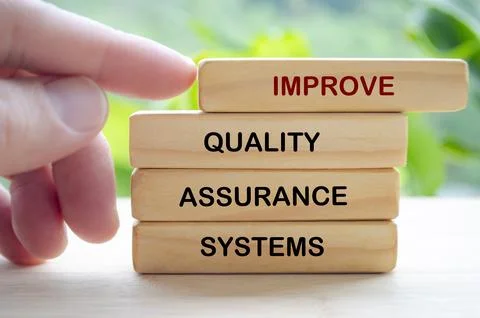 Improve Quality Assurance Systems text on wooden blocks representing contin.. Stock Photos