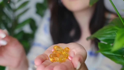 Improve your morning routine with essential vitamins! A woman holds Omega and B Stock Footage 267229161