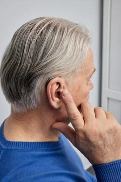 Improving hearing with hearing aids. Hearing aid behind-the-ear of elderly ma Photos
