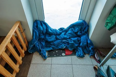 Improvised winter draft stop with blue duvet at glass patio door Foto stock