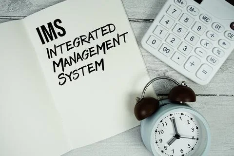 IMS Integrated Management System text on paper notebook page with alarm clo.. 스톡 사진