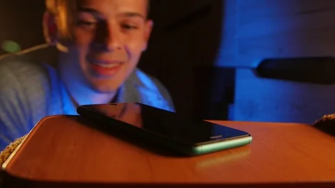 Inattentive boy looking around for a lost smartphone in a dark room Stock Footage 106153701