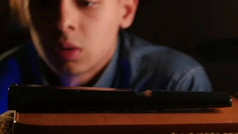 Inattentive young guy looking around for a lost remote TV controller at night in Video stock 106470787