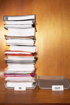 Inbox with stack of paperwork empty outbox on desk Foto stock
