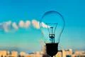 The incandescence bulb by the industrial city background Photo