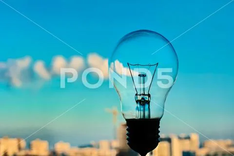 The incandescence bulb by the industrial city background Stock Photos