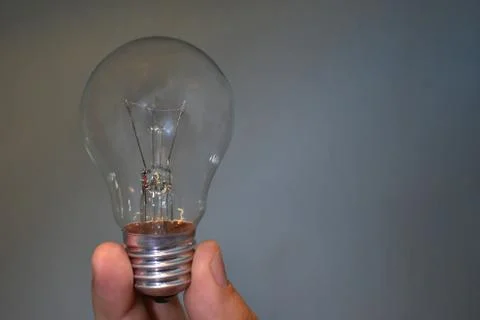 Incandescent bulb in hand on empty background Stock Photos