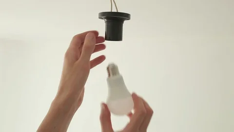 Incandescent lamp is changed to LED light by the hands of a man. Energy saving. Stock Footage 109421161