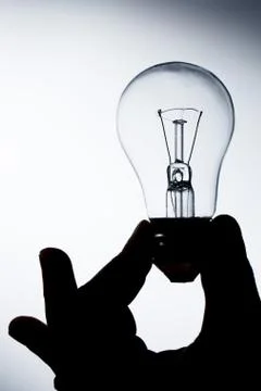 Incandescent lamp in a hand on a gradient background Stock Photos