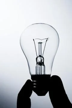 Incandescent lamp in a hand on a gradient background Stock Photos