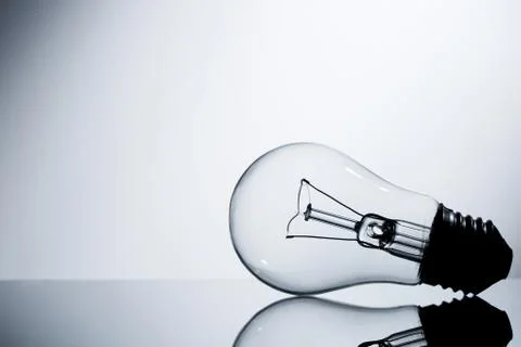 Incandescent lamp lying on a table on a gray gradient background Stock Photos