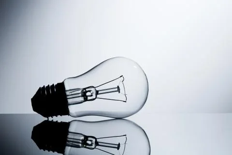 Incandescent lamp lying on a table on a gray gradient background Stock Photos