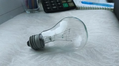 An incandescent lamp is on the table, a calculator is in the background. the Stock Footage 316286660