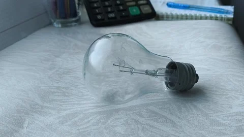 An incandescent lamp is on the table, a calculator is in the background. the Stock Footage 316286698