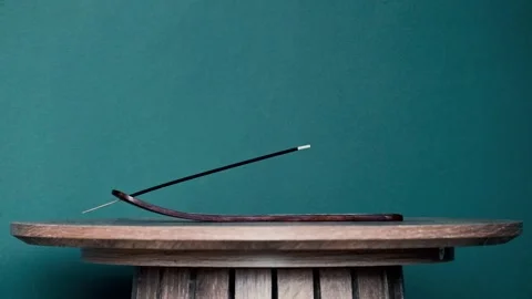 Incense burning against a dark teal background Stock Footage 345077341