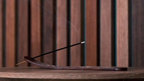 Incense burning against a wooden backdrop Stock Footage 345074396