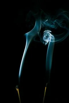 Incense smoke creates a variety of pattern shapes on a black background Stock Photos