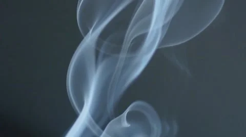 Incense smoke twirling as it burns in front of a plain white wall. Stock Footage