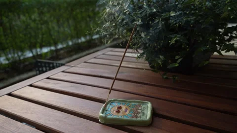 The incense stick smokes in an esoteric clay holder with the sun painted on it Stock Footage 249965707