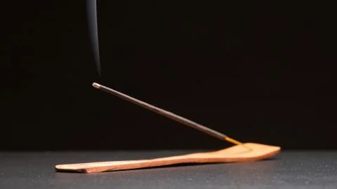 Incense stick smokes on a table Stock Photos