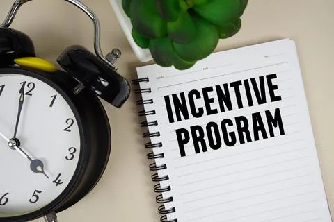 Incentive program text written on notepad with alarm clock Stock Photos