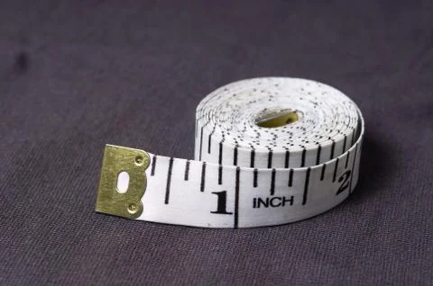 Inch, centimeter tape on a background of grey fabric Stock Photos