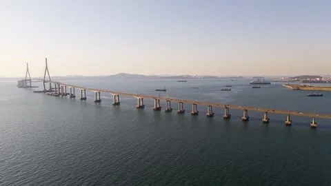 Incheon Bridge spans calm bay with cruise ship and cargo vessels below Stock Footage 340199756